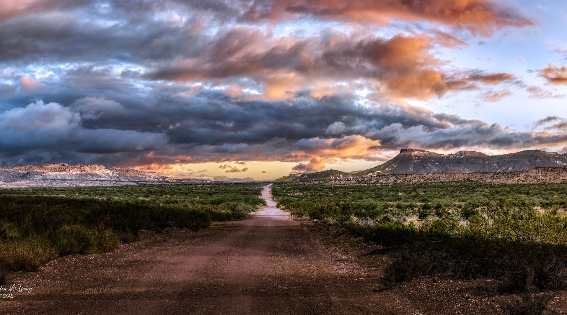 Dirt road into Big Bend country under storm clouds at sunset.