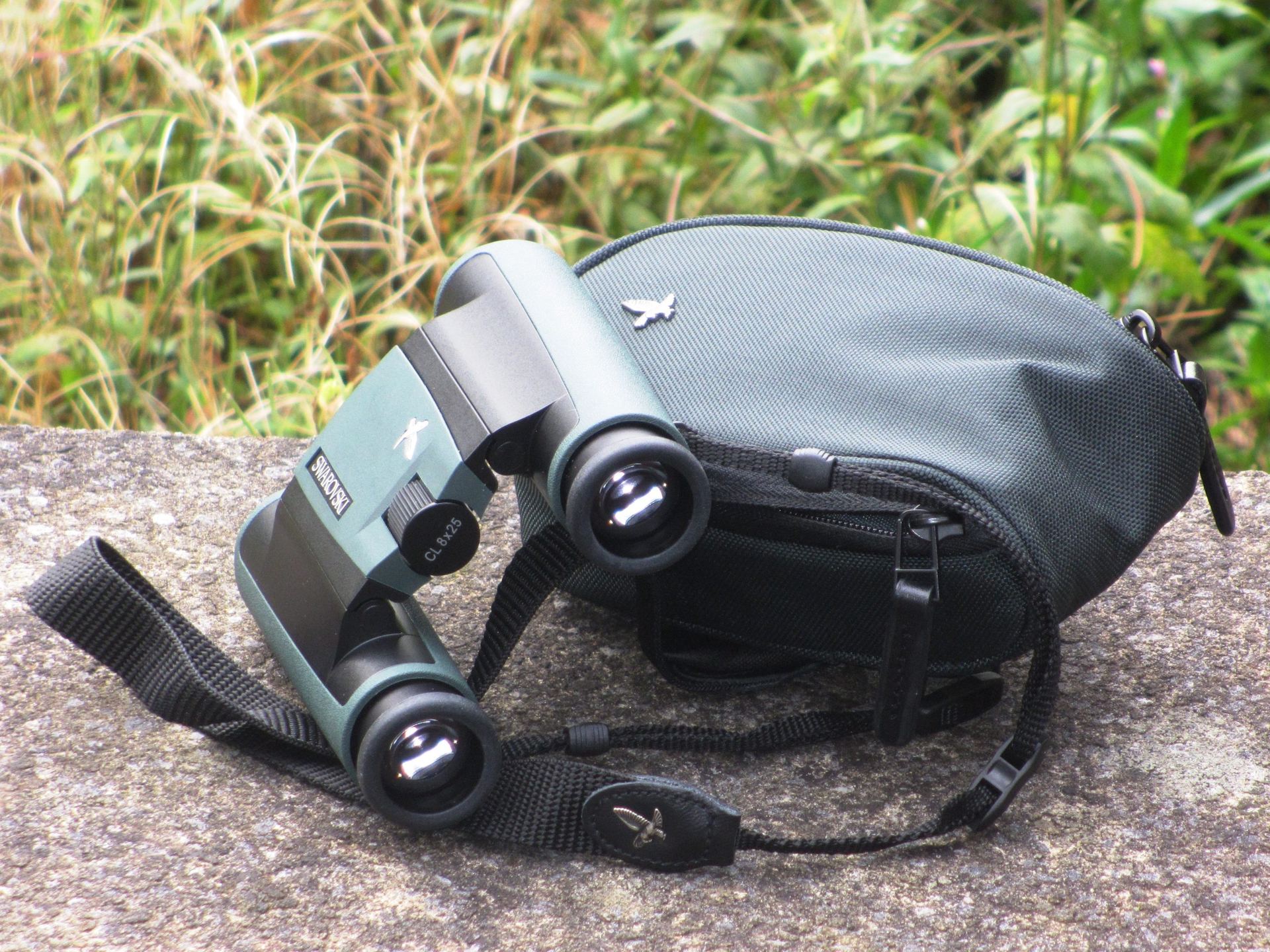 Swarovski compact binoculars resting on a stone ledge.